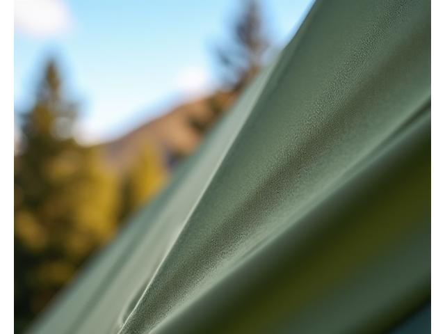 Close-up of a sustainable tent fabric, showing its texture and green color, indicating eco-friendliness.